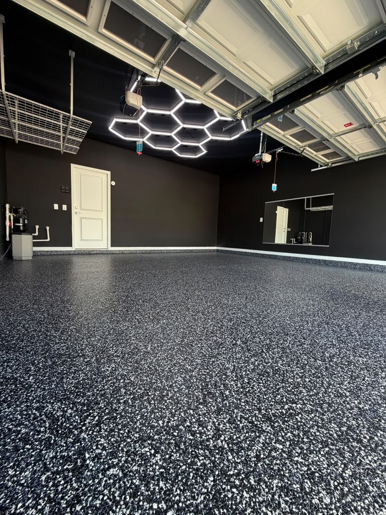 Garage with black-and-white flake epoxy floor, charcoal walls, and hexagon LED ceiling lights