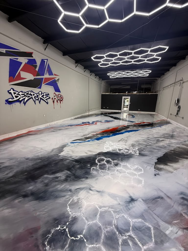 Commercial auto shop with white, grey, red, and blue metallic epoxy floor under hexagon lights